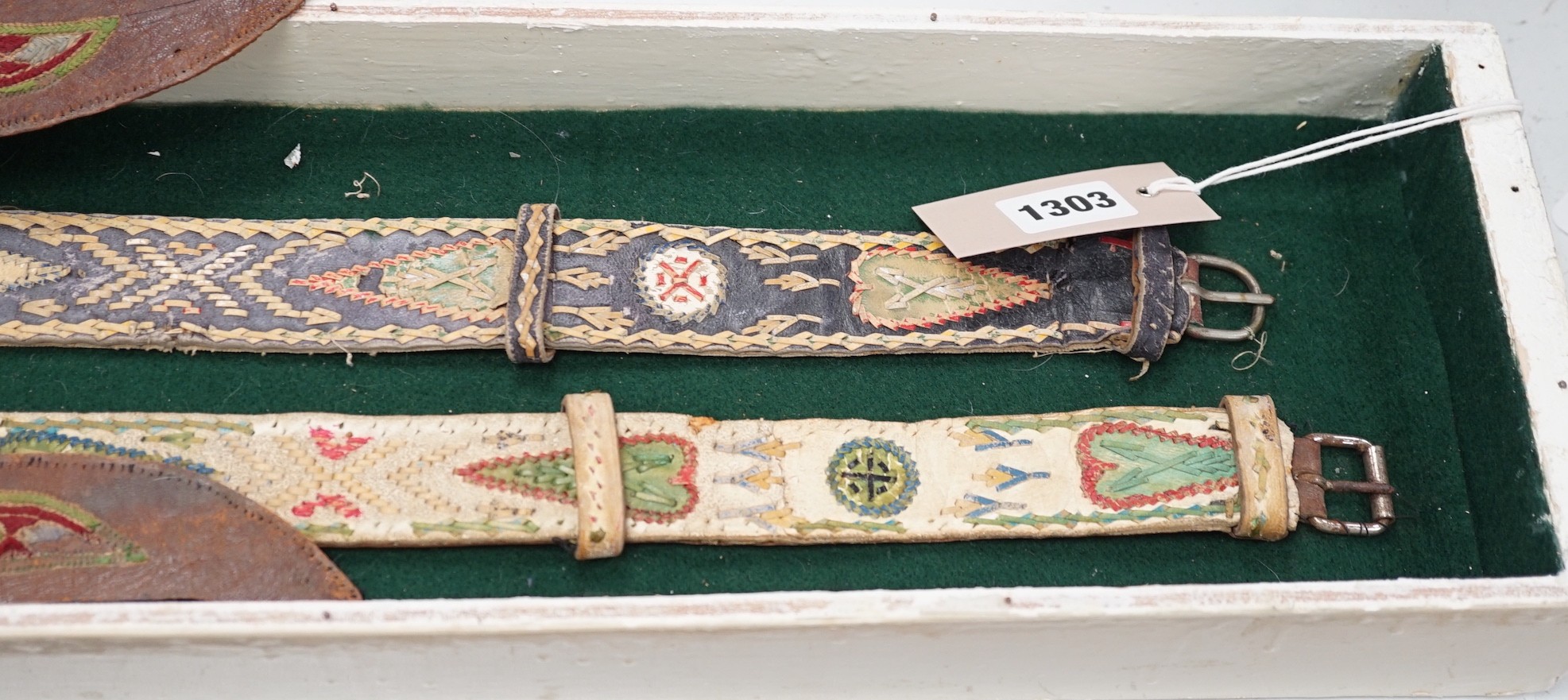 A two framed native American Indian ornately woven and embroidered leather belts and a pair of leather embroidered slipper fronts, longest belt 103cms